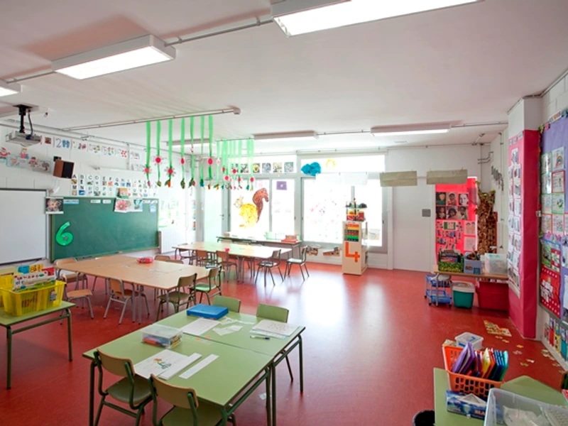 Aula d’infantil amb taules petites i materials de joc i descoberta.