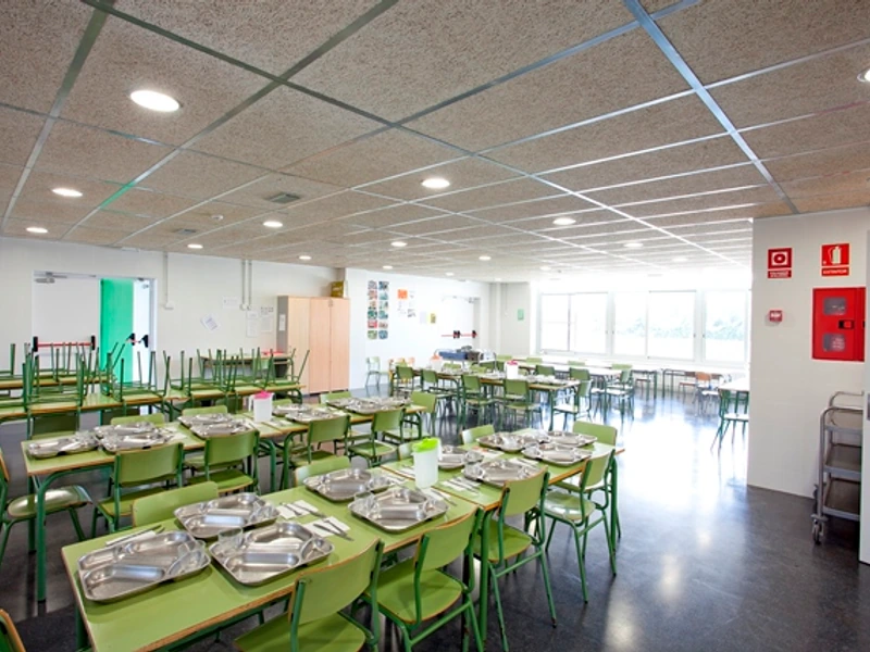 Menjador de l’escola amb les taules i els coberts preparats.