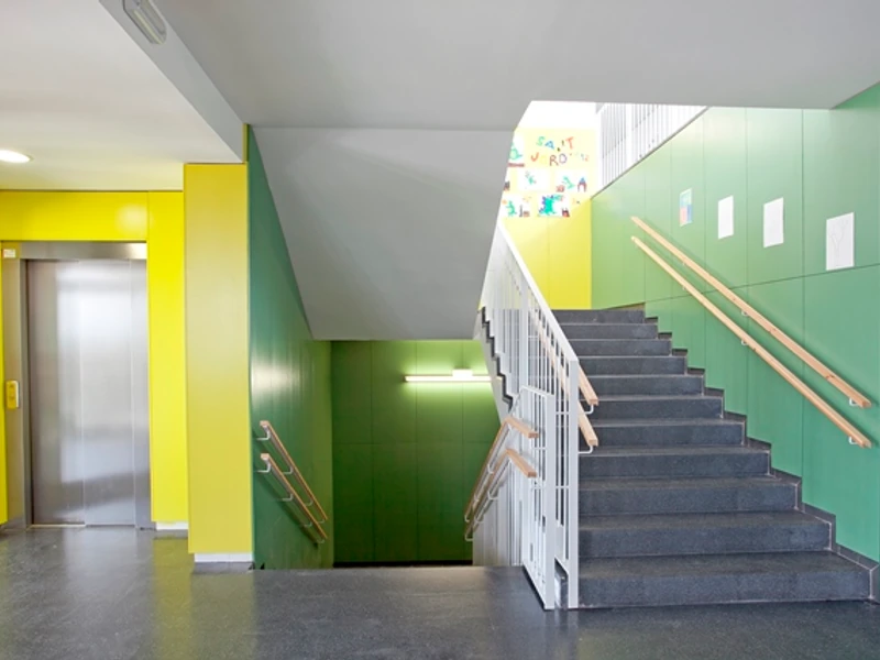 Escala interior de l’escola amb parets verdes i grogues.