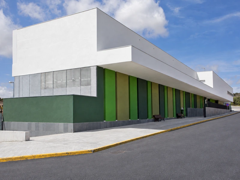 Façana de l’escola Font-rúbia, amb el volum blanc i els pilars verds.