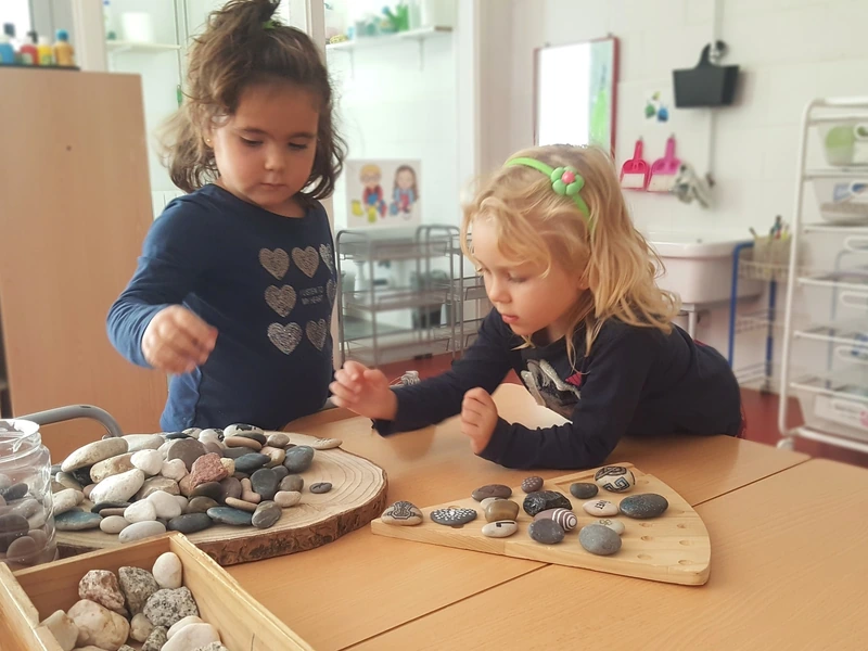 Dues nenes manipulen pedres i materials naturals en una activitat d’experimentació.
