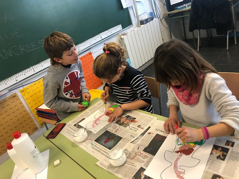 Tres alumnes treballen amb materials en una activitat compartida a l’aula.